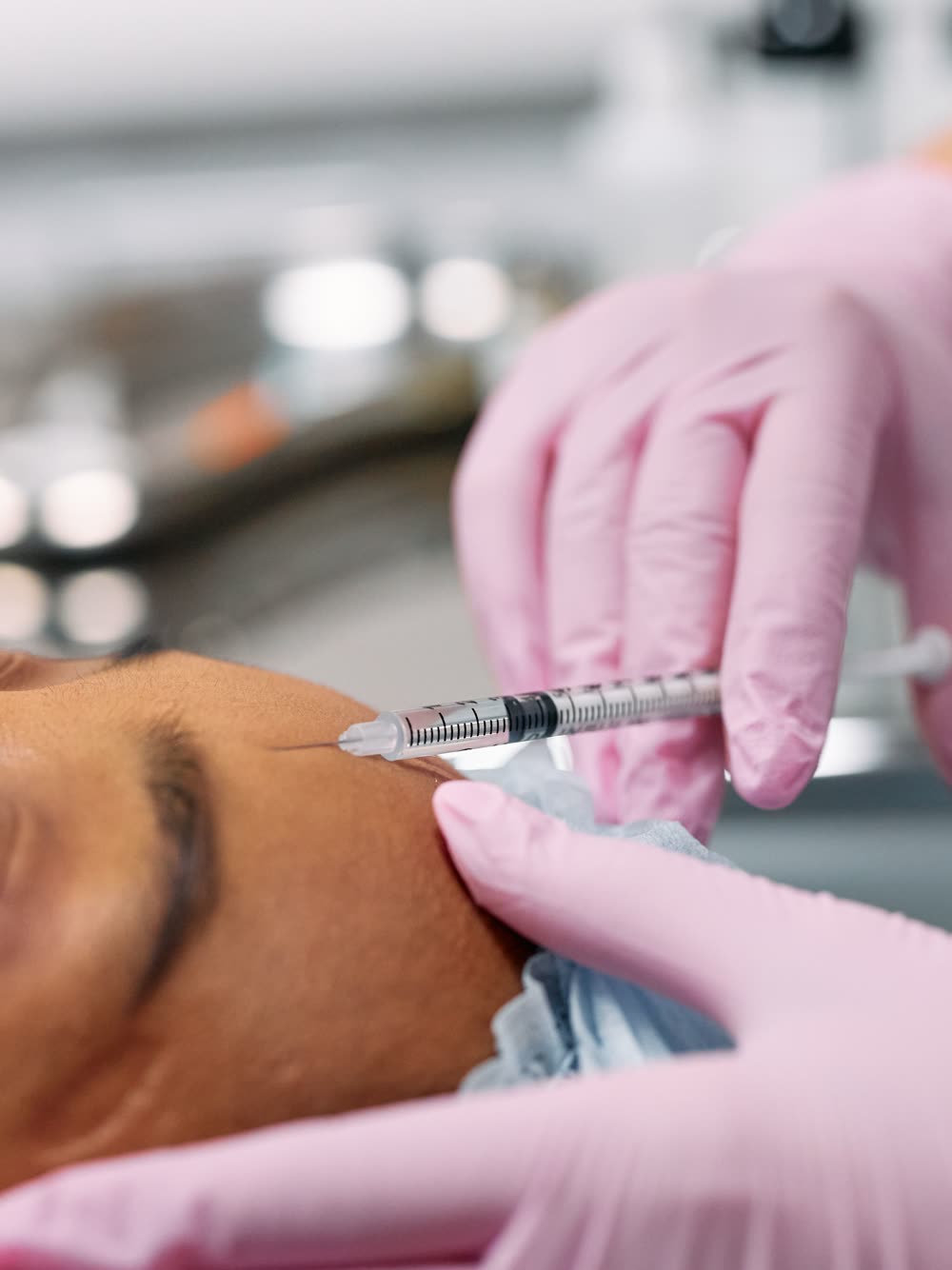 Aplicación médica de un inyectable facial con guantes estériles